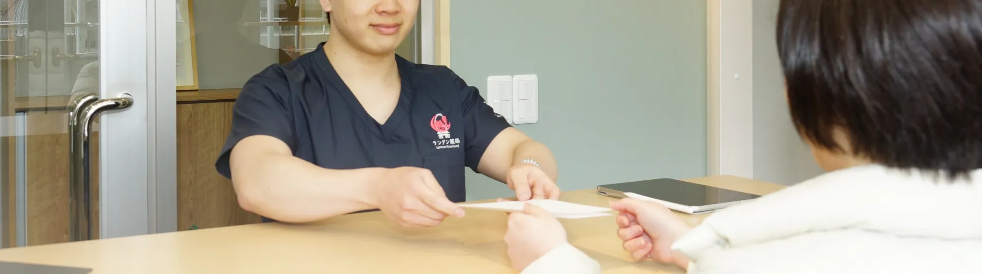 A pharmacist at Lantern Pharmacy handing out medicine to a patient