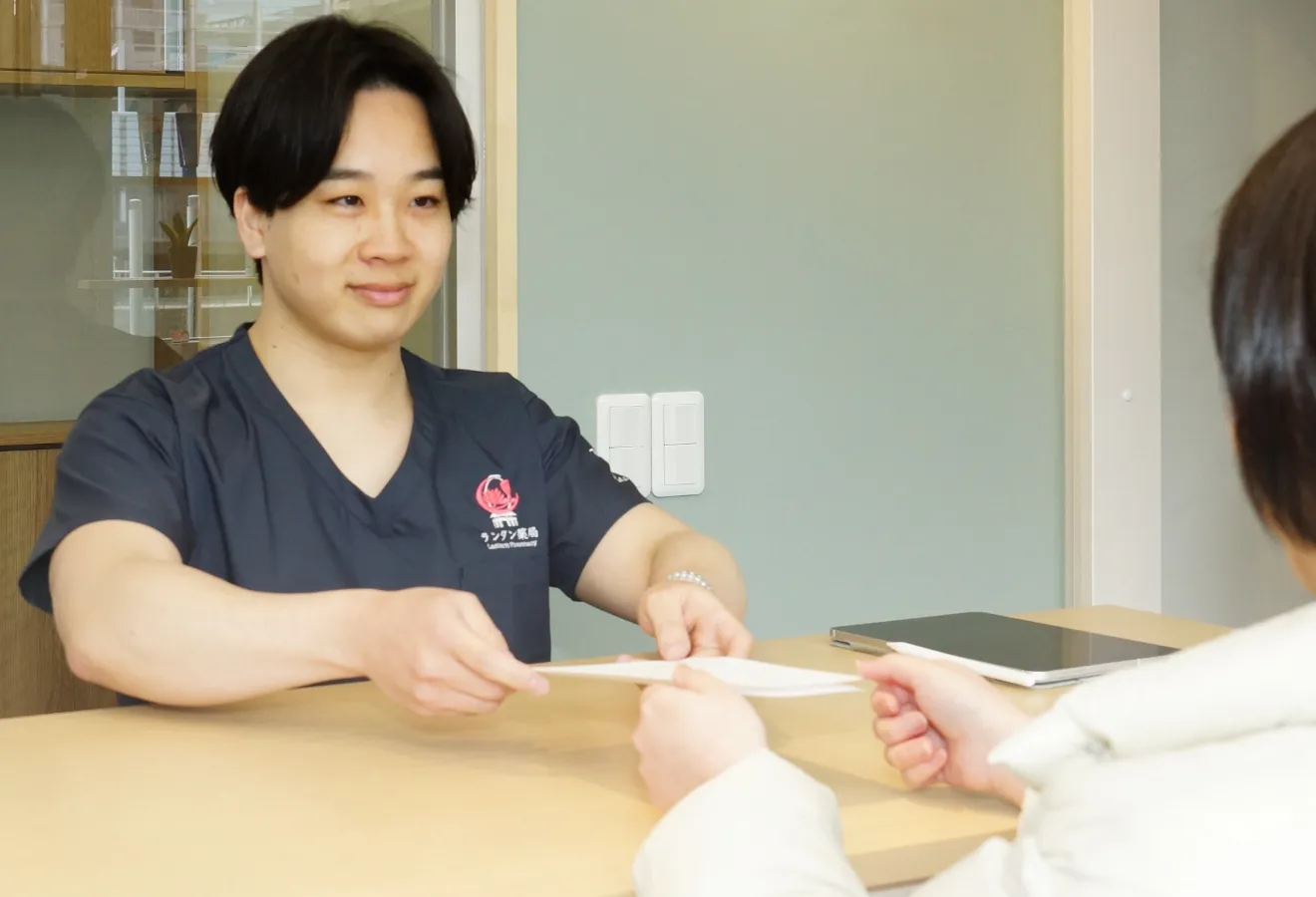 A pharmacist at Lantern Pharmacy handing out medicine to a patient